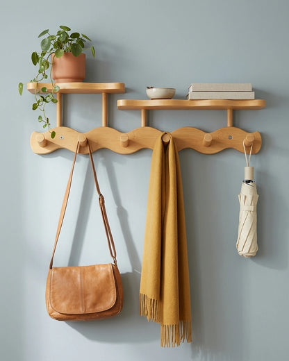 Natural bamboo wavy coat rack with two shelves holding a plant, books, a leather bag, a mustard scarf and an umbrella on a blue-grey wall
