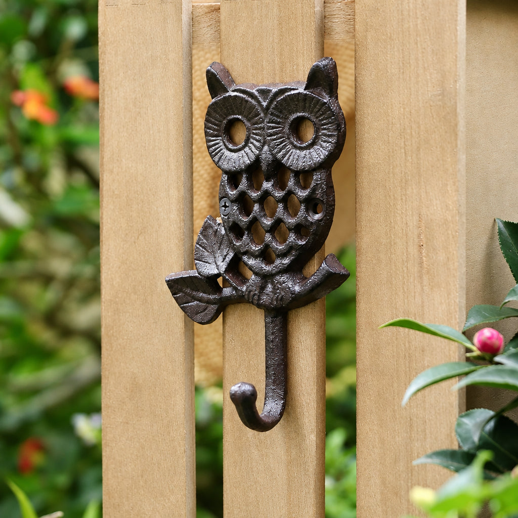 Slim cast iron owl wall hook with a single hook, mounted on a wooden garden fence