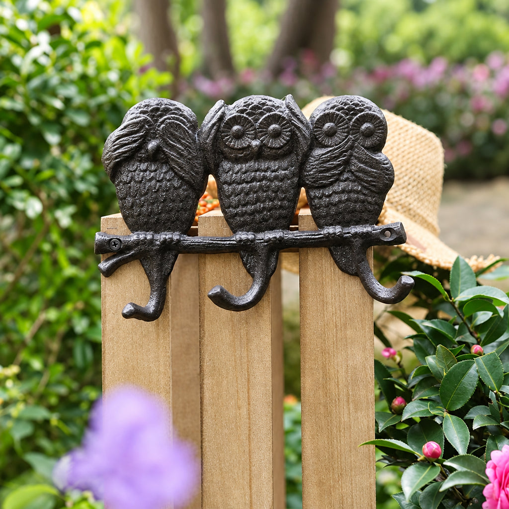Cast iron wall hook with three owls on a branch and three hooks, mounted on a wooden fence
