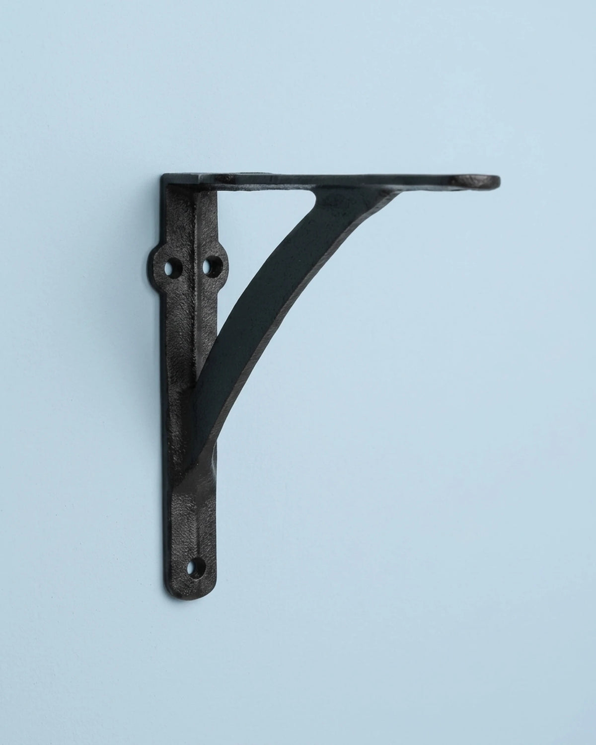 Arc black cast iron shelf bracket with a curved support on a soft pastel powder blue background