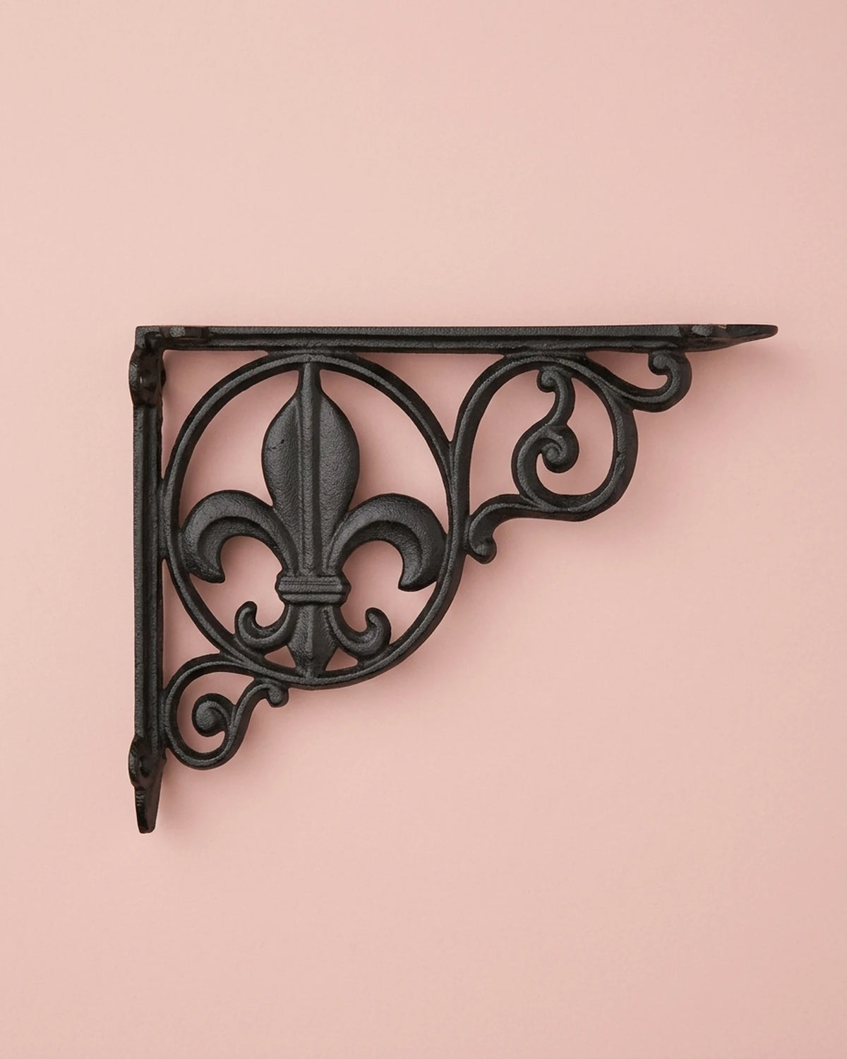 Fleur-de-lis black decorative shelf bracket on a soft blush pink background